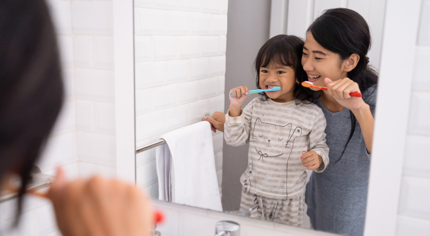beautiful mother and daughter brushing teeth in the bathroom sink before going to bed